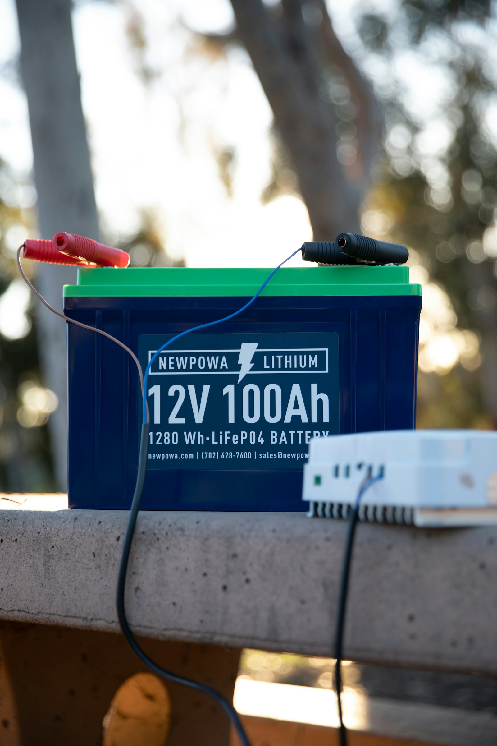 A smart charger connected to a 12V battery with red and black clamps